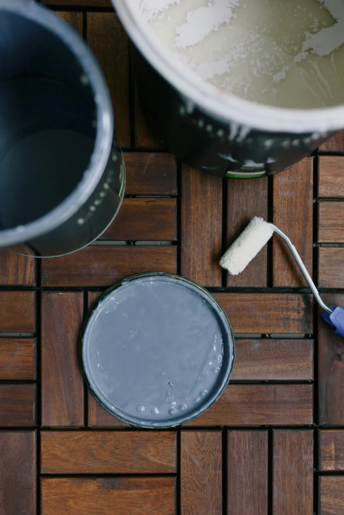 A can of gray paint on a dark tiled floor, ready to be used by an Austin residential painter