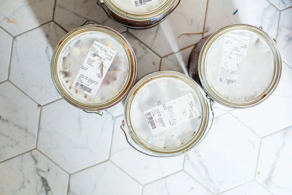 cans of white paint resting on a tiled floor, ready to be used by a residential painter in Austin, TX