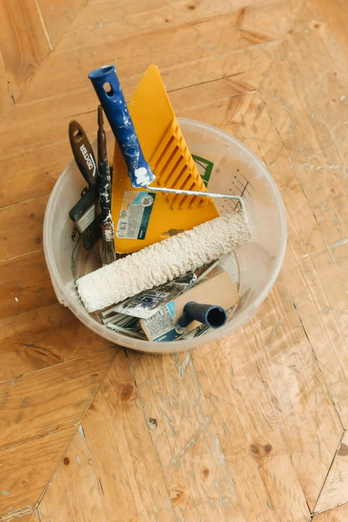 A bucket full of house painting supplies