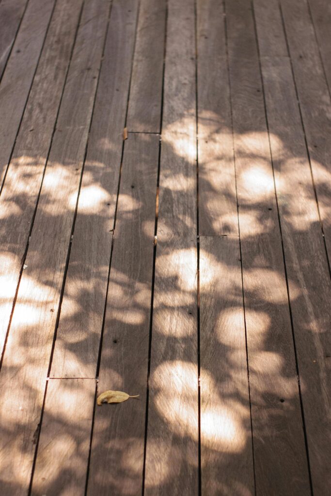 A stained deck with sunlight through leaves on it