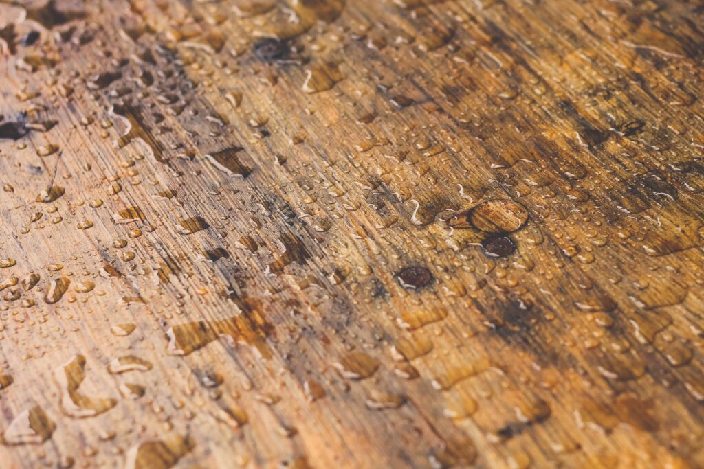 A stained deck with beads of water on it