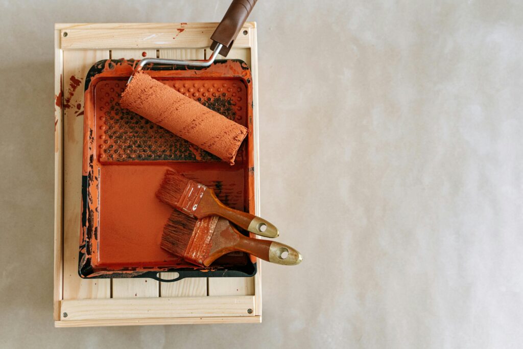 A photo of an orange paint brush and roller brush